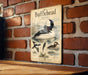 A vintage-style metal sign with illustrations of ducks and other wildlife, mounted on a brick wall.