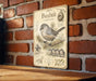 a vintage-style metal sign with illustrations and text, mounted on a brick wall.