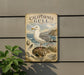 A vintage-style metal sign with a seagull illustration, mounted on a wall next to a plant.