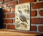 a vintage-style metal sign with a California quail illustration, mounted on a brick wall.