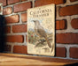 A vintage-style metal sign with illustrations of birds, including a California thrush, mounted on a brick wall.