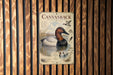 a poster with a duck illustration and text, mounted on a wooden wall.