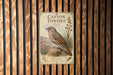 A vintage-style sign for "Canyon Towhee", featuring a bird illustration and text, is displayed on a wooden wall.