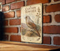 a vintage-style metal sign with a bird illustration, mounted on a brick wall.