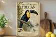 A vintage-style poster of a toucan, featuring a detailed illustration of the bird and its natural habitat, is displayed on a wall next to a wooden cutting board and some kitchen utensils.