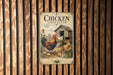 A vintage-style poster of a chicken coop and rooster is displayed on a wooden wall.