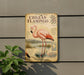 a sign with a detailed illustration of a pink flamingo, accompanied by text and a map, mounted on a wall.