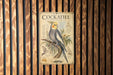 A vintage-style poster of a Cockatiel, a small parrot, is displayed on a wooden wall.