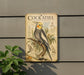 a vintage-style metal sign with illustrations and text, mounted on a wall next to a plant.