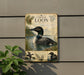 a vintage-style sign depicting a loon, a bird often found in lakes and rivers in North America. The sign is mounted on a wall and includes illustrations of the bird and its natural habitat.