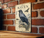 a vintage-style metal sign with a black raven illustration and various bird-related text and graphics, mounted on a brick wall.
