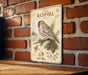 a vintage-style metal sign with a bird illustration and botanical illustrations, mounted on a brick wall.