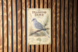 a vintage-style sign for the Diamond Dove, a small, gray bird with a white chest and tail, perched on a branch.