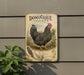 a vintage-style sign for Dominique chicken, which is mounted on a wall next to a plant.