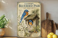 a vintage-style poster of a bluebird nest with a wooden birdhouse, displayed on a shelf next to a potted plant and kitchen utensils.