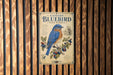 A vintage-style sign with an illustration of a bluebird and berries, mounted on a wooden wall.