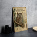 a metal sign with an illustration of an Eastern Screech- Owl, surrounded by text and illustrations, placed on a table next to some black camera lenses.