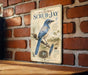 A vintage-style sign for Florida scrub-jay birds, featuring an illustration of a blue bird perched on a branch with a nest and eggs.