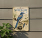 A vintage-style metal sign with illustrations of a blue bird, pine cones, and a nest, mounted on a wall.