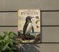a penguin standing on a rock, with a plant in the foreground.