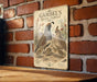 A vintage-style metal sign with an illustration of a family of quails, including a mother, father, and two young birds, mounted on a brick wall.
