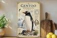 a poster of a penguin on a shelf, with a potted plant to the left and a wooden cutting board to the right.