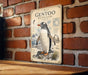 a vintage-style metal sign with an illustration of a penguin, mounted on a brick wall.