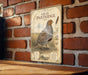 a vintage-style metal sign with a detailed illustration of a gray partridge standing on a grassy field.