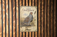 a vintage-style metal sign with an illustration of a gray and brown bird, likely a partridge, standing in a grassy field.