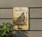 a vintage-style metal sign with a detailed illustration of a gray partridge standing in a field, surrounded by tall grass and wildflowers.