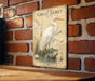a vintage-style illustration of a great egret, a large wading bird, standing on a brick wall.