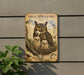 A vintage-style metal sign with an illustration of a great horned owl and its nest, mounted on a wall next to a plant.