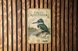 A vintage-style poster of a kingfisher bird is displayed on a wooden wall.