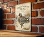A vintage-style metal sign with an illustration of a green-winged teal duck, mounted on a brick wall.
