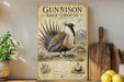 a vintage-style metal sign with an illustration of a Gunnison Sage-Grouse, a bird native to the western United States. The sign is mounted on a wall and is surrounded by various kitchen items, including a potted plant, a cutting board, and a bowl of lemons.