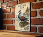 A vintage-style illustration of a Harlequin duck is displayed on a brick wall, with a wooden table below it.