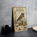 A metal sign with illustrations and text about a bird called "Harris's Sparrow" is displayed on a table.
