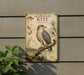 a metal sign with a detailed illustration of a bird, specifically a Hook-Billed Kite, perched on a branch.