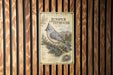 a metal sign with a bird illustration, mounted on a wooden wall.