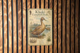 a poster of a khaki Campbell duck, which is mounted on a wooden wall.