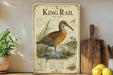 A wooden shelf displaying a framed illustration of a King Rail bird, surrounded by kitchen utensils and a potted plant.