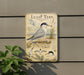 a sign with a detailed illustration of a tern, a small seabird, standing on the ground with its wings spread. The sign is mounted on a wall, and there is a plant to the left of the sign.