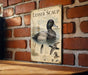 A vintage-style metal sign featuring an illustration of a Lesser Scaup duck, with text describing the bird's features and habitat.