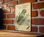 A vintage-style metal sign with an illustration of a colorful parrot, mounted on a brick wall.