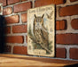 a vintage-style illustration of a long-eared owl perched on a branch, with a brick wall in the background.
