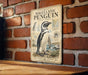 A vintage-style poster of a Magellanic penguin is displayed on a brick wall, featuring illustrations and text about the species.
