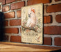 a vintage-style metal sign with a detailed illustration of a cockatoo perched on a branch, surrounded by flowers and foliage.