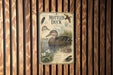 a vintage-style metal sign with illustrations and text about ducks, mounted on a wooden wall.