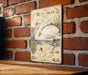 a vintage-style metal plaque with an illustration of a swan and text, mounted on a brick wall.
