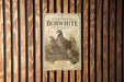 A vintage-style metal sign with illustrations of Northern Bobwhite quails and other birds, mounted on a wooden wall.